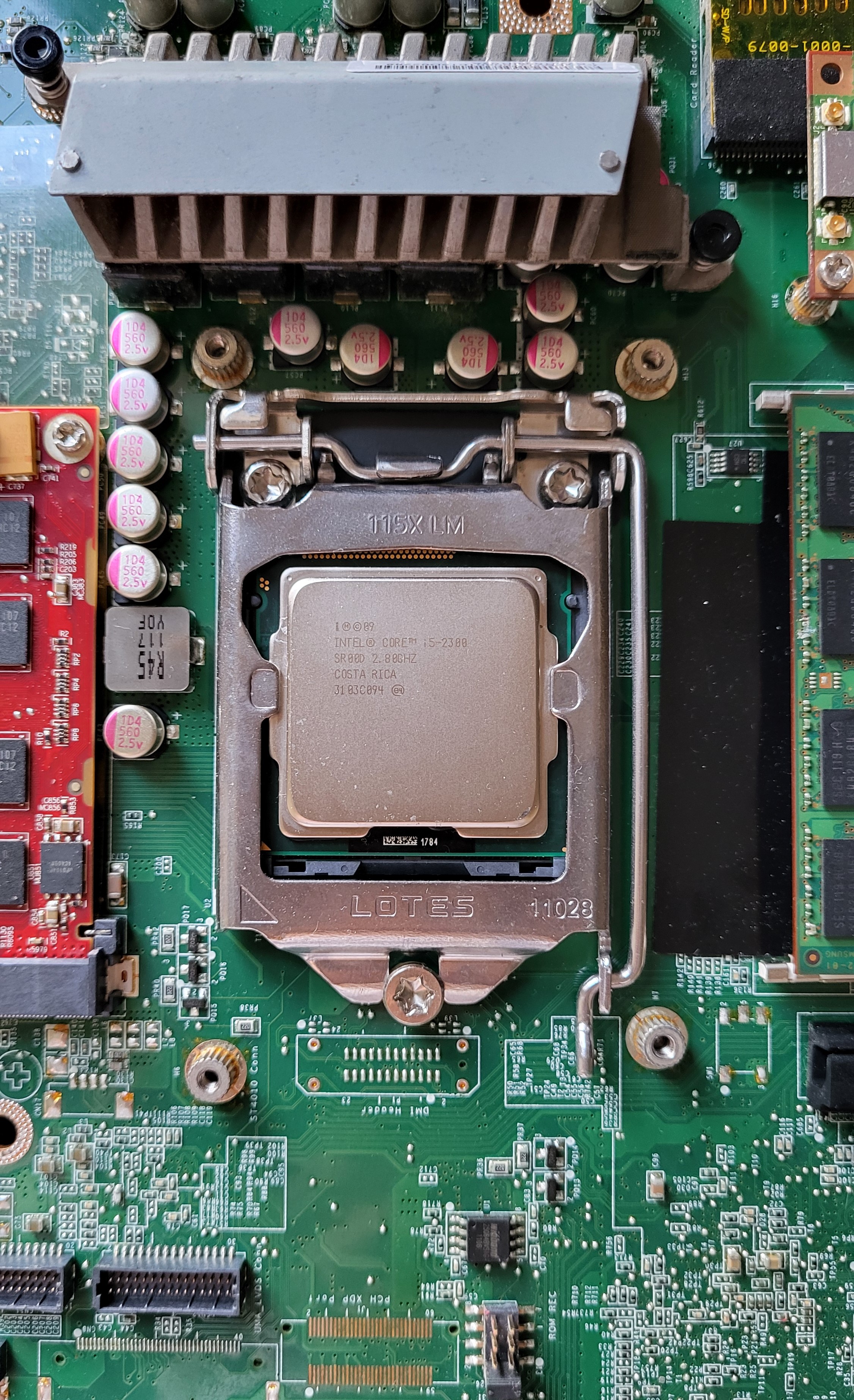 A closeup view of the square, nearly-flat silver-colored metal cpu chip, fixed inside its closed case on the computer's motherboard.